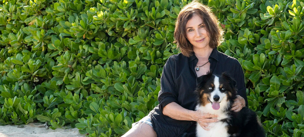 Kim McDonald sitting with her dog on the beach.