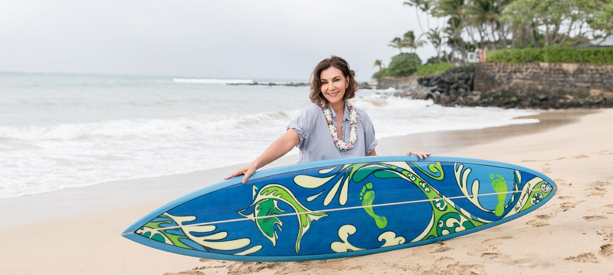 Kim McDonald posed on the beach with a custom painted surfboard.